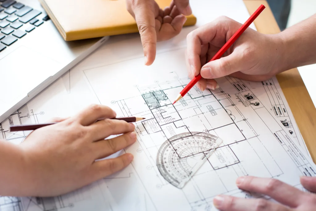 Architects reviewing a construction blueprint with pencil and protractor — DesignTech Global architecture design services USA